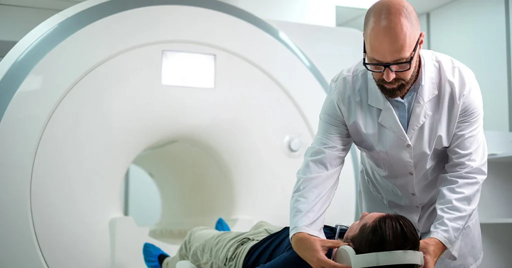 Male Technologist Puts Headphones On Male Patient During MRI Scan