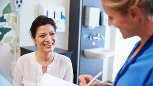 Patient Service Representative Talking To Smiling Female Patient Before Appointment