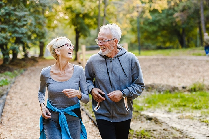 Older Couple Jogging In The Park Together