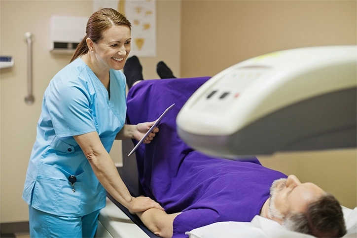 Technologist Smiling At Patient While He Undergoes DEXA Scan